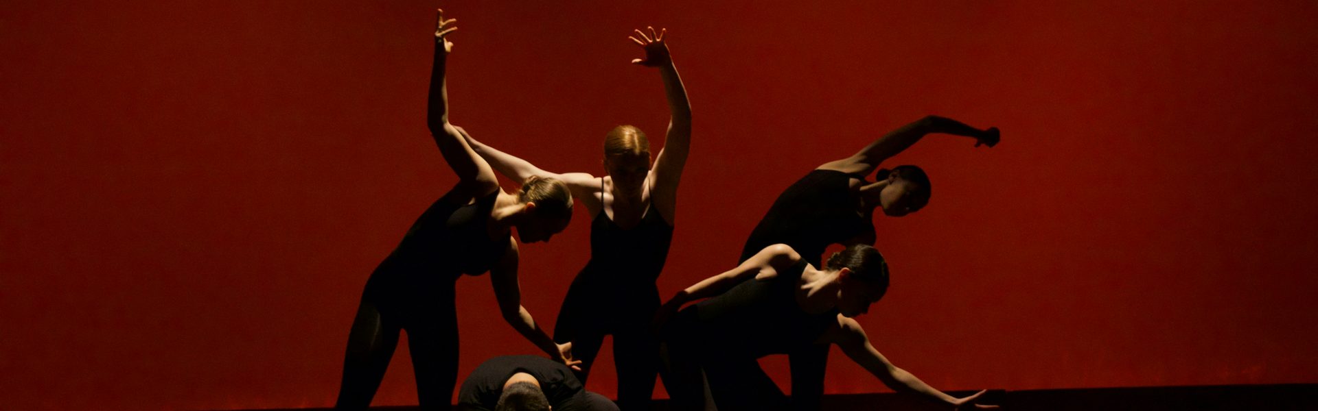 Dancers frozen mid-performance against a red stage backdrop
