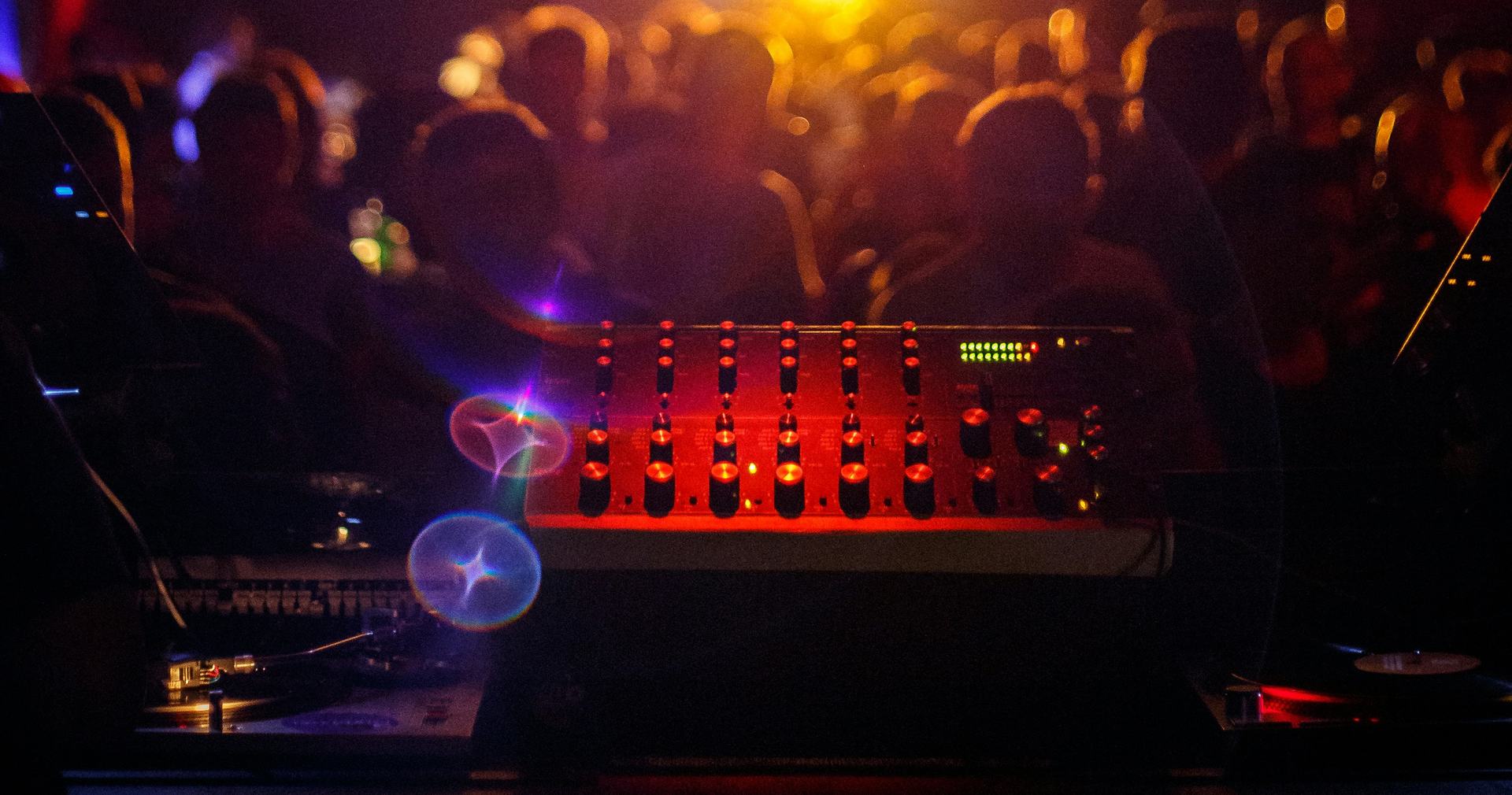A packed club crowd under mirror balls and blue laser beams