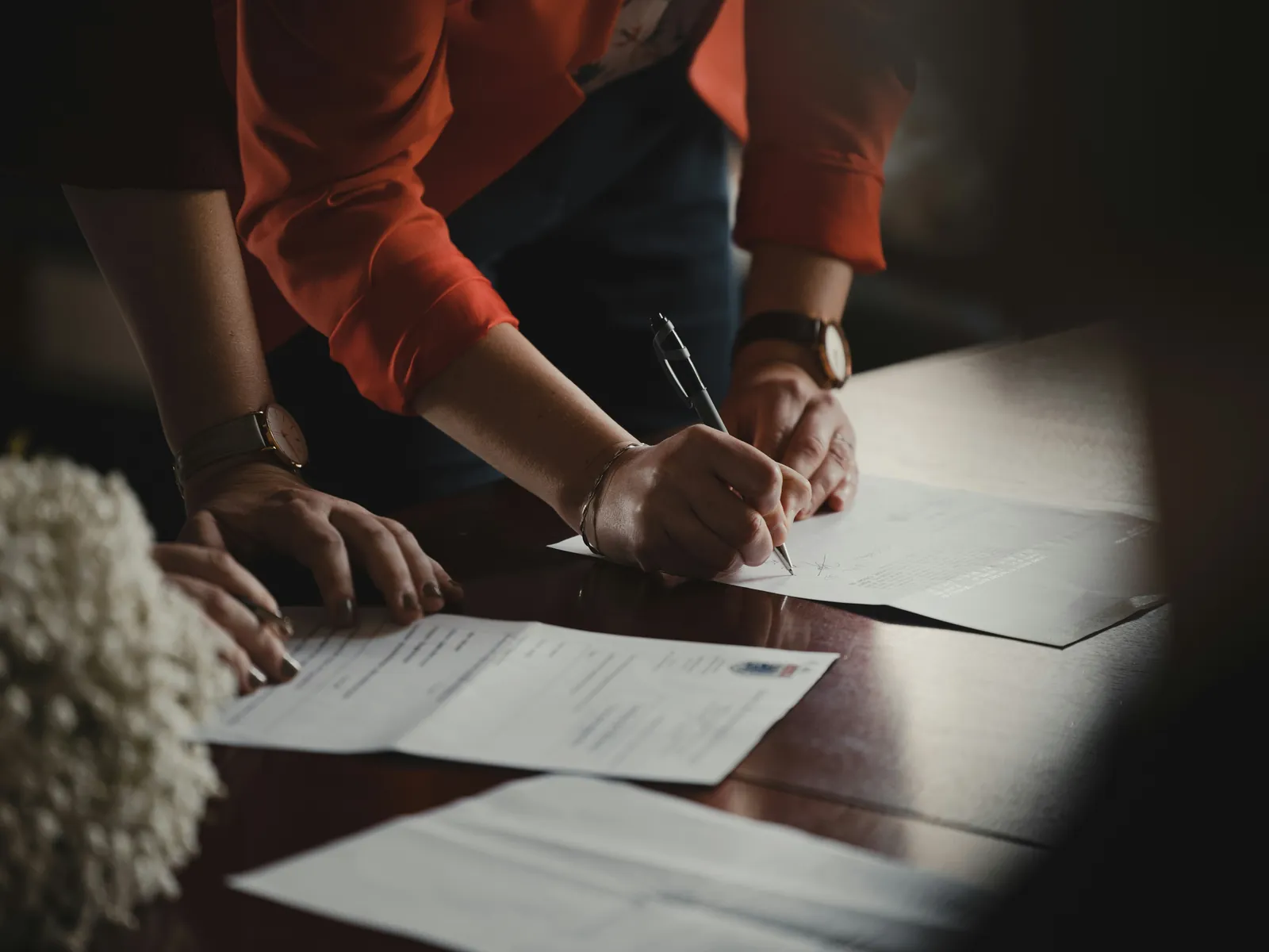 Two people leaning over a desk signing paperwork