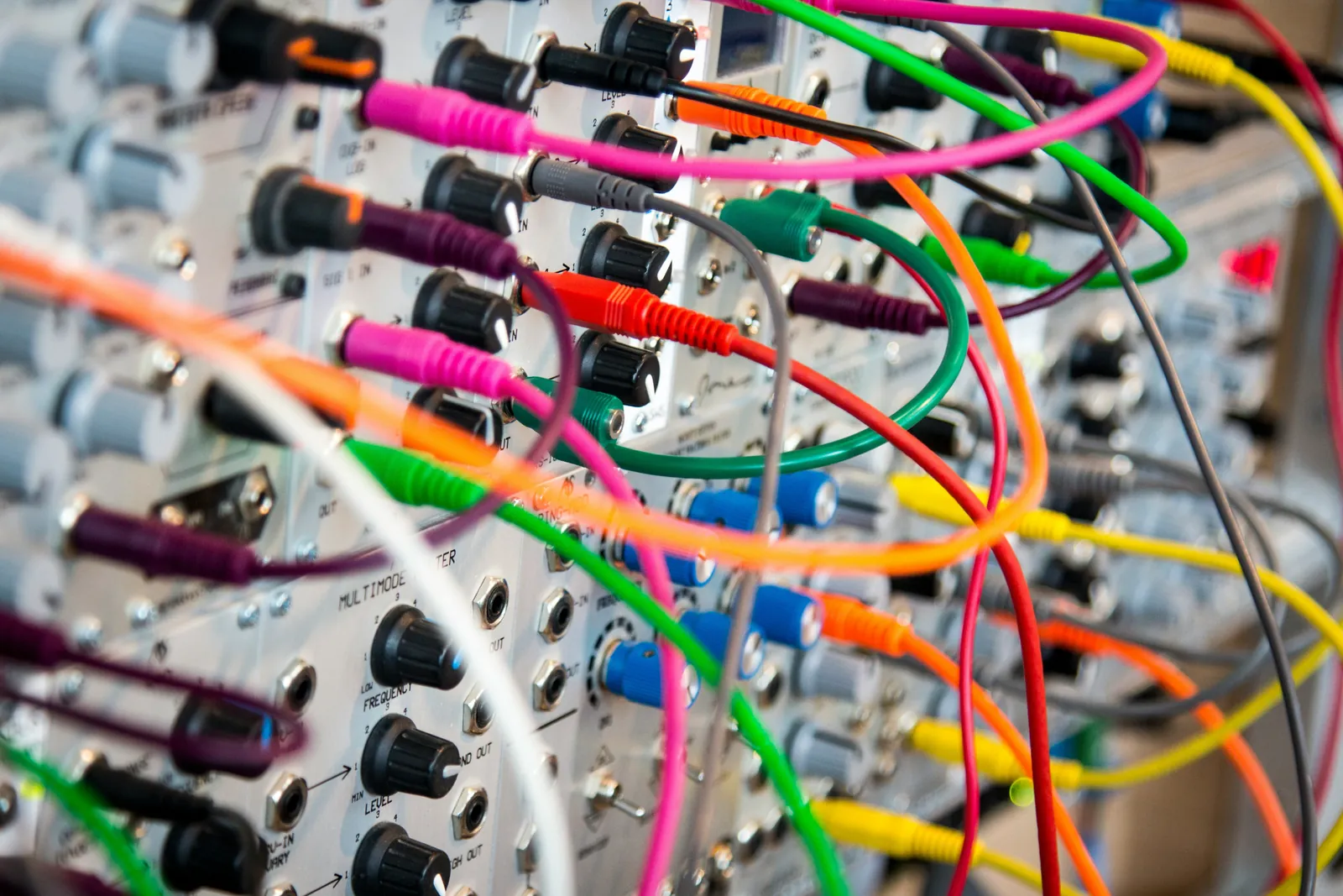 A modular synthesiser buried under a tangle of brightly coloured patch cables